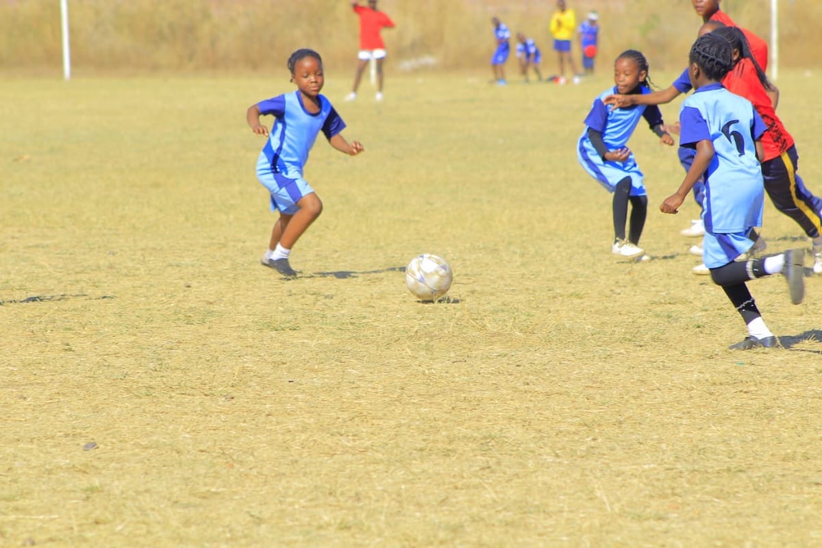 Primary girls playing football on a school pitch